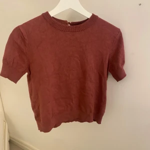 Röd kortärmad tröja från Divided - Säljer en stilren röd tröja från Divided. Den har korta ärmar och en rund halsringning med ribbade kanter. Perfekt för en avslappnad look.