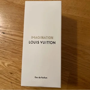 Imagination Eau de Parfum från Louis Vuitton - Exklusiv parfym från Louis Vuitton, Imagination, i en elegant glasflaska med svart lock. Förpackningen är stilren och vit med märkets logotyp i silver. Flaskan rymmer 100 ml av denna lyxiga doft.
