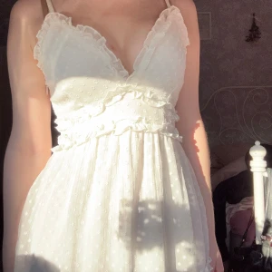 Vit klänning/studentklänning - söt vit klänning med volanger och prickar som passar perfekt till studenten eller midsommar🥰 storlek XS men passar även S och har justerbara axelband, använd extremt fåtal gånger så i super bra skick!🫶 kom privat för eventuella frågor!