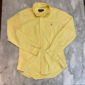 Gul Ralph Lauren skjorta  - Skick: 8,5/10. Skjortan är i bra skick och har inga defekter. Från märket Ralph Lauren i storlek M. Om du är osäker på om det kommer att passa kan du alltid fråga om mått!