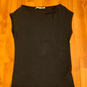 ärmlös topp  - Snygg och enkel svart ärmlös topp från lager 157. Perfekt för en stilren look, med en bekväm passform och mjukt material. Båt ringad. Storlek M.