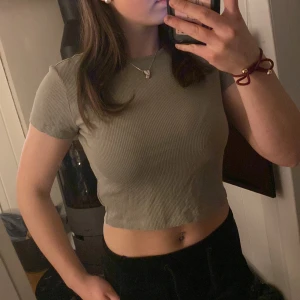 Topp från H&M - Säljer en grön knappt använd ribbad topp från H&M Divided. Den har en croppad passform och korta ärmar.💕