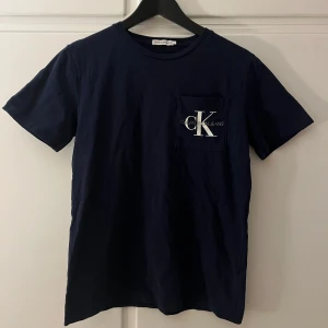 Mörkblå t-shirt, Calvin Klein Jeans - Snygg mörkblå t-shirt från Calvin Klein Jeans med en stilren bröstficka och logotyp. 