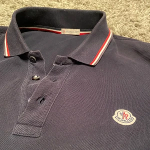 Mörkblå pikétröja från Moncler - Säljer nu denna moncler polo som är äkta, men de finns lite tecken på användning kam skicka privat, hör av er vid frågor! Pris kan diskuteras!
