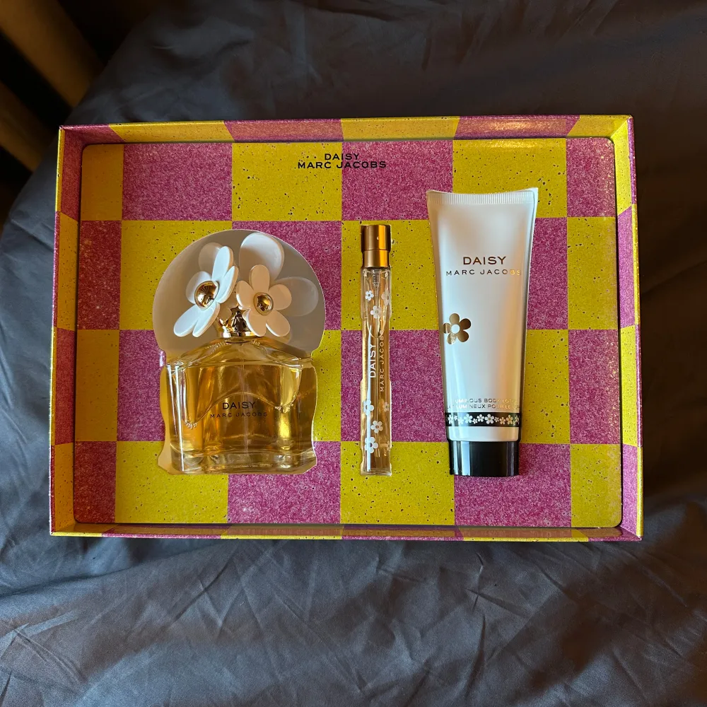 Säljer ett Daisy parfymset från Marc Jacobs. Setet innehåller en flaska parfym på 100ml med en vacker blomformad kork, en mindre resestorlek 10ml och en kroppslotion på 75ml och allt är i samma doft. Förpackningen har ett färgglatt rutmönster i rosa och gult. Perfekt för den som älskar blommiga dofter! 🌼Jag säljer för att jag köpte fel doft från daisy! Och kittet är helt bytt!🩷 . Perfume.