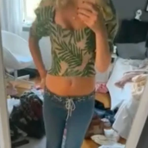 Grön och vit blus med bladmotiv - Trendig blus med grönt och vitt bladmotiv. Den har puffiga ärmar och en knytning i ryggen. Perfekt för en somrig look!