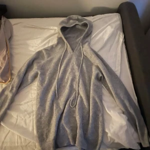 Grå hoodie Merinoull - Säljer en stilren grå hoodie med långa ärmar och justerbar huva. Perfekt för en avslappnad look. Passar bra till jeans eller andra casual outfits.