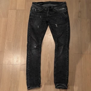 Svarta jeansbyxor med slitningar - Snygga svarta jeansbyxor från Dondup med snygga slitningar för en trendig look. De har en slim passform och klassisk femficksdesign. Perfekta för en avslappnad stil.