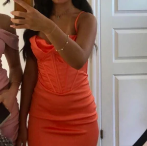 Orange tight klänning - Säljer en snygg orange klänning med smala axelband och en tight passform. Klänningen har en figurnära design som framhäver formerna.