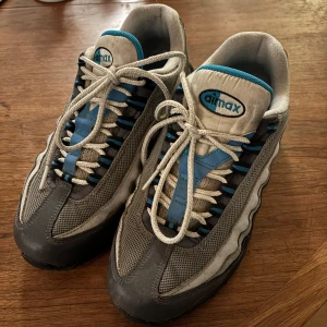 Nike Air Max skor - Säljer ett par Nike Air Max sneakers i grått och blått.  Slitna där bak men inget som märks när man använder dom