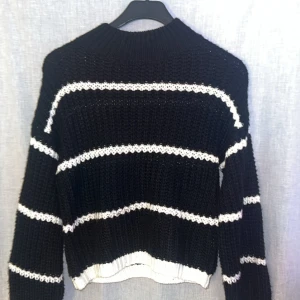 Svart och vit randig stickad tröja - Säljer en snygg svart stickad tröja med vita ränder. Tröjan har långa ärmar och en bekväm passform. Perfekt för kyligare dagar. Hör av dig vid intresse!