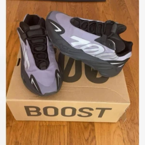 Adidas YZY 700 MNVN i lila och svart - Snygga Adidas YZY 700 MNVN sneakers i en cool lila och svart färgkombination. Skorna har en unik design med snörning och en chunky sula för extra komfort och stil. Storlek 36