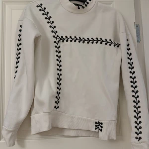 Vit sweatshirt - Säljer en stilren vit tröja med svarta detaljer som löper längs ärmarna och över bröstet. Från Topshop i storlek 34.