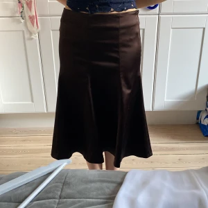 Brun kjol från Coast - Snygg brun kjol från Coast i en elegant och klassisk stil. Kjolen har en slät yta och en lätt utsvängd form som ger en fin silhuett. Perfekt för att skapa en stilren look. Storlek S