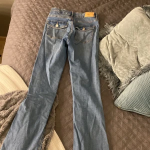 Blå jeans med bootcut - Snygga blå jeans med bootcut-stil och klassiska femficksdesign. De har en knapp och dragkedja framtill samt dekorativa sömmar på bakfickorna. Perfekta för en avslappnad look. Kan fixa mer bilder hur dom sitter på, pris kan sänkas 