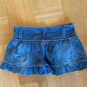 Jeanskjol från MNG Jeans - Säljer en superfin jeanskjol från MNG Jeans i storlek 38. Skulle uppskatta till större S/mindre M. Kjolen är kort och har en söt volangdetalj längst ner. Den är i en klassisk blå jeansfärg och har praktiska fickor fram. Perfekt för en avslappnad sommarlook eller en cool våroutfit. Passar både till vardags och fest! Verkligen så fin o har inga defekter 💓