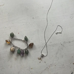 Halsband - Säljer 2 halsband, ett med stenar/kristaller och ett silverfärgat med ett diqmanthjärta. Köp en för 40 eller båda för 65