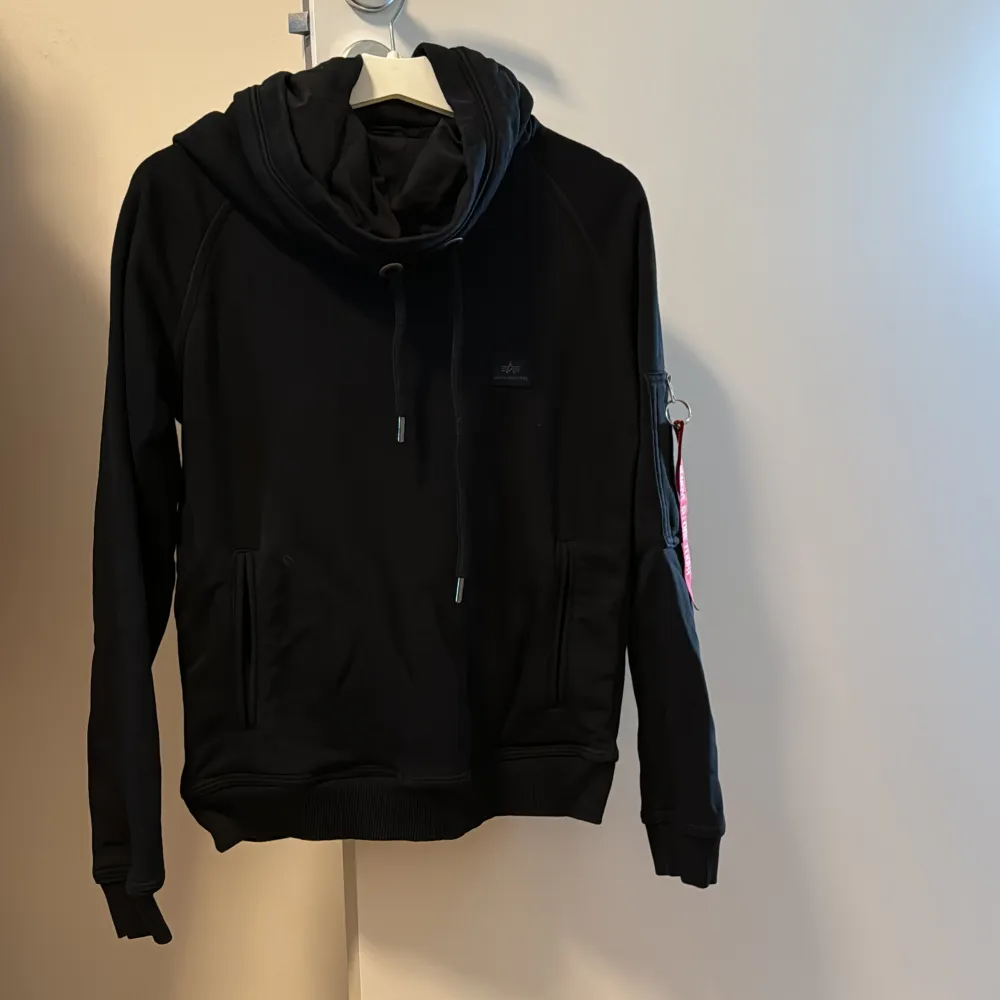 Svart hoodie från Alpha Industries. Fint skick. Storlek XS, passar nog också S. Hoodien har 2 fickor framme och 1 på vänster arm. Stor luva. . Hoodies.