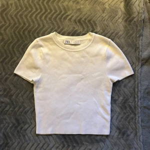Vit kortärmad topp från Zara - Säljer en stilren vit topp från Zara i storlek S. Den är kortärmad och har en enkel, klassisk design och något åt det croppade hållet. Mycket mjuk och bekväm mot huden. Lite tjockare tyg skulle jag säga. 💗