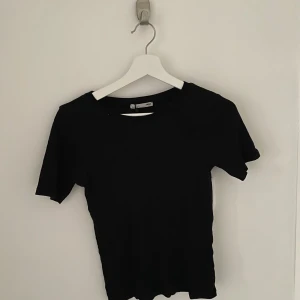 Svart kortärmad topp från Zara - Säljer en enkel och stilren svart topp från Zara. Den är kortärmad och har en normal passform. Toppen är i bra skick.