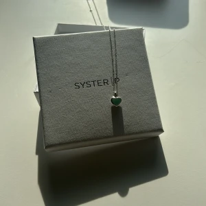 Hjärt halsband   - Säljer mitt fina Syster P halsband som är ett grönt hjärta. Använd fåtal gånger och är som ny. 