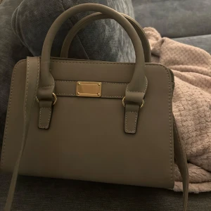 Grå väska  - Jätte fin grå väska, den har även ett långt axelband ifall man skulle vilja använda det.