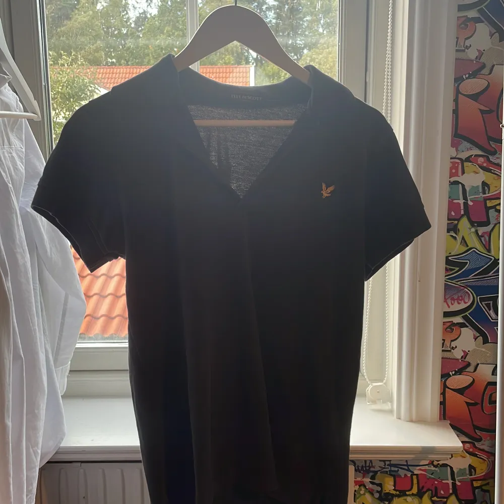 Säljer en stilren svart t-shirt från Lyle & Scott i storlek S. Den har en liten gul logga på bröstet och är kortärmad. Perfekt för en casual look!. T-shirts.