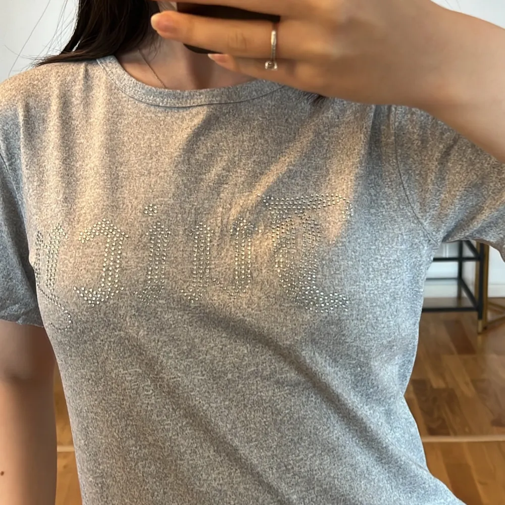 Säljer en snygg grå t-shirt med glittrig text på framsidan. Den är kortärmad och har en normal passform, perfekt för vardagsbruk. Materialet känns mjukt och  bekvämt. Passar bra till jeans för en avslappnad look.💞. T-shirts.