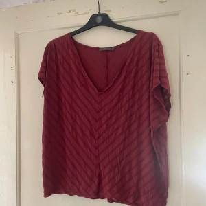 Vinröd topp från frk. - Säljer en vinröd topp från frk. i storlek XL. Den har en v-ringad hals och ett diskret randigt mönster. Perfekt för både vardag och fest!
