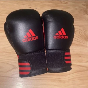 Adidas boxnings handlar  - Dessa boxningshandskar (12 oz) använde jag under en 3 månaders tidsperiod på jag tränade boxning för 3-4 år sedan. De är i bra skick med endast ett par små repor som knappast märks. Köpte dessa på Stadium.