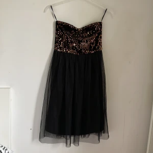 Svart paljettklänning från ONLY - Säljer en superfin svart klänning från ONLY i storlek XS. Den har en glittrig överdel med massor av paljetter som verkligen fångar ljuset. Klänningen är axelbandslös och har en luftig kjol i ett lätt material. Perfekt för fest eller nyår! ✨