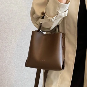 Kaffebrun bucket bag - Present som aldrig kommit till användning. Flera fack, knappar och förlängning av axelbandet tillkommer. I bubbelplast och tyg påse💕