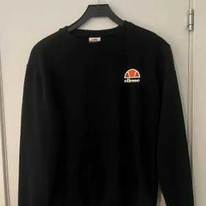 Svart sweatshirt från Ellesse - Säljer en stilren svart sweatshirt från Ellesse med deras ikoniska logga på bröstet. Tröjan har långa ärmar och en klassisk rund halsringning. Storlek S