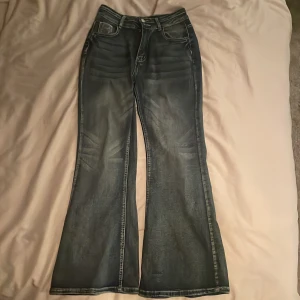 Blå bootcut jeans med broderade fickor - Snygga blå bootcut jeans med unika broderade detaljer på bakfickorna. Jeansen har en klassisk femficksdesign och en bekväm passform. Perfekta för en avslappnad stil.