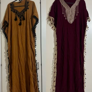 Två klänningar med broderier - Säljer två eleganta kläningar . Den ena är senapsgul med svarta broderier och tofsar, medan den andra är vinröd med detaljerade broderier i beige. Passar upp till xxl och super fint skicks 