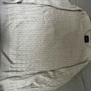 Benvit kabelstickad tröja från Bondelid - Säljer en stilren benvit stickad tröja från Bondelid. Tröjan har ett klassiskt kabelstickat mönster och långa ärmar med ribbade muddar vid ärmslut och nederkant. Perfekt för kyligare dagar. Knappt använd, säljes pga att den numera är för stor för mig.