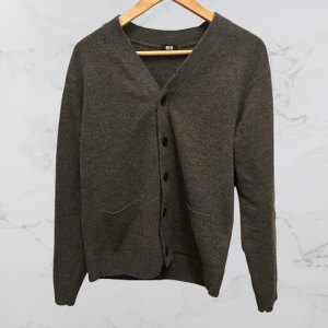 Grå cardigan från Uniqlo - Säljer en stilren grå kofta från Uniqlo i storlek S. Koftan är tillverkad av 100% ull och har en v-ringad design med knappar framtill. Sprillans nytt skick, använd en gång. Perfekt för kyligare dagar. Priset är inte satt i sten. Hör av er. du minsta fundering!