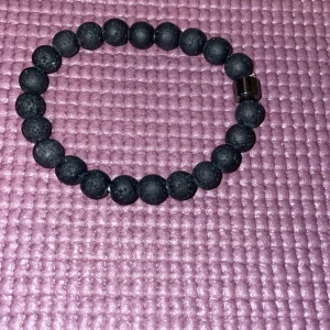 Svart pärlarmband - Snyggt svart armband med runda pärlor och en metallisk detalj. Perfekt för att ge en stilren touch till din outfit.