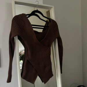 Brun ribbad omlottopp - Säljer en snygg brun ribbad omlottopp med långa ärmar. Perfekt för en stilren look. Toppen har en unik omlottdesign som ger en modern touch.
