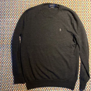 Grå tröja från Polo Ralph Lauren - Säljer nu denna coola tröja från Ralph Lauren👔 Tröjan är gjord av merinoull som är känt för sin höga kvalitet och förmåga att hålla dig varm🐑 Tröjan visar inga tecken på slitage. Skicka ett meddelande till mig vid minsta fundering👑