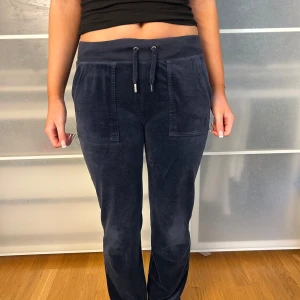 Mörkblå  Juicy Couture mjukisbyxor med snörning - Priset går att diskuteras! Säljer ett par mörkblå mjukisbyxor i mjukt material med snörning i midjan. Byxorna har fickor både fram och bak, vilket ger en avslappnad look. Perfekta för en bekväm dag hemma eller en avslappnad utflykt.