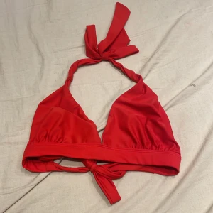 Röd bikiniöverdel från Åhléns - Snygg röd bikiniöverdel från Åhléns med knytband i nacken och ryggen. Perfekt för en dag på stranden eller vid poolen. Den har en enkel och stilren design som ger en bekväm passform.