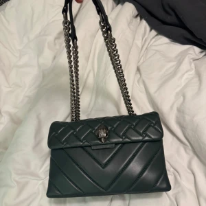 Grön axelväska från Kurt Geiger - Snygg grön axelväska från Kurt Geiger med quiltad design och kedjeaxelrem. Färgen finns inte att köpa längre. Inga tecken på användning. Väldigt fint skick. Storlek medium