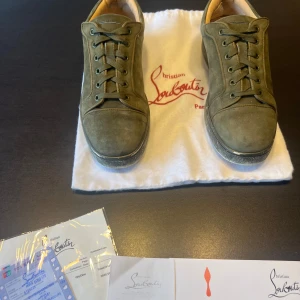 Christian Louboutin - Snygga gröna sneakers från Christian Louboutin med den ikoniska röda sulan. Skorna har snörning och är tillverkade i mocha. Perfekta för dig som vill ha en stilren och lyxig look.