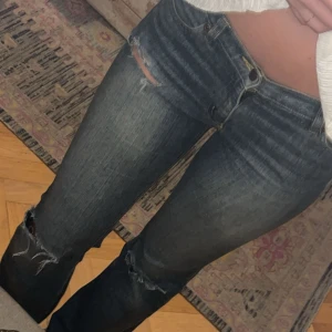 Mörkblå jeans med slitningar - Snygga mörkblå jeans med slitningar på knäna. De har en klassisk femficksdesign och en knappgylf. Perfekta för en avslappnad stil.