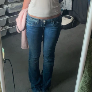 Blå bootcut jeans - Snygga blå bootcut jeans med låg midja. Perfekta för en avslappnad stil. De har klassiska fem fickor och en dragkedja med knapp framtill.