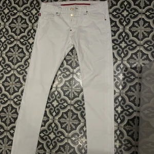 Tramarossa Leonardo W33 - Snygga vita byxor från Tramarossa i modellen Leonardo. Vita jeans med röda detaljer och guldknappar. Materialet är 100% bomull. Jeansen är i mycket bra skick.