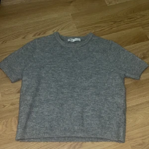 Grå stickad tröja från Zara - Säljer en stickad tröja från Zara kort i ärmarna och super skön att ha på sig för en avslappnad look🩶