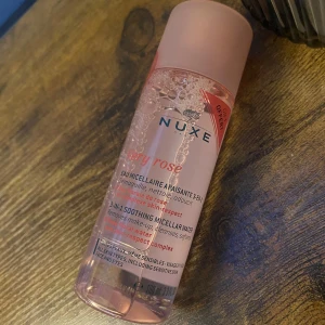 Nuxe Very Rose 3-in-1 Soothing Micellar Water - Säljer en flaska Nuxe Very Rose 3-in-1 Soothing Micellar Water, helt oanvänd. Denna rengöringsvatten är perfekt för känslig hud och tar bort smink effektivt. Innehåller rosextrakt för en skonsam och lugnande effekt. Flaskan är genomskinlig med rosa detaljer och har en praktisk skruvkork.