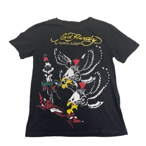Svart t-shirt med örnmotiv från Ed Hardy - Snygg svart t-shirt från Ed Hardy med ett stort, detaljerat tryck av örnar. Utöver trycket så är tröjan även fylld med rhinestones som får trycket att poppa mer.